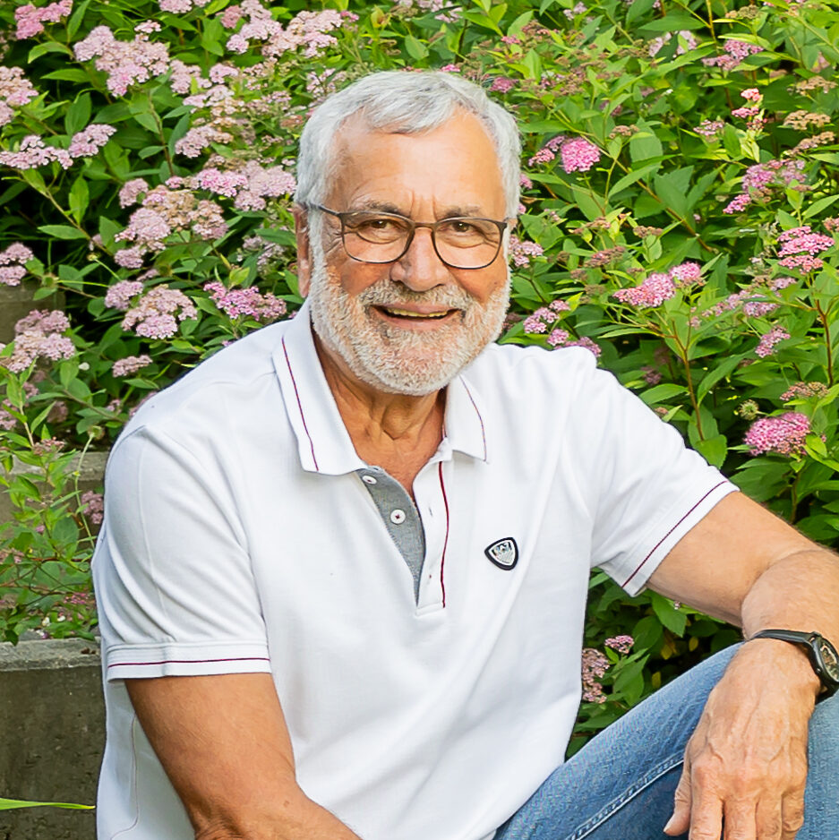 Wolfgang Fredl im Garten zwischen blühenden Sträuchern.
